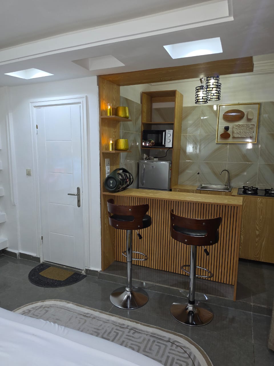 Fitted kitchen bar with gas hob, microwave, fridge and two stools
